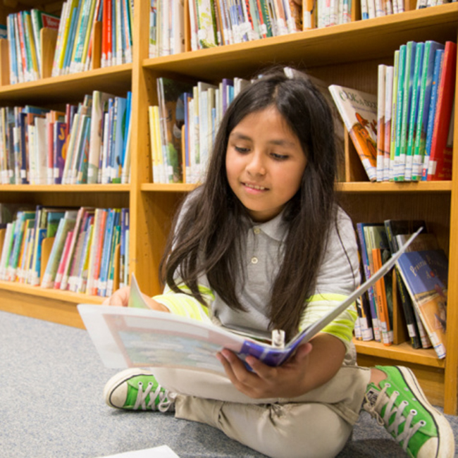 girl student sitting on the floor and reading a book